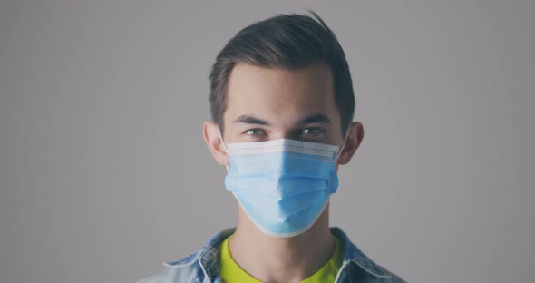 Happy Young Male Removes the Face Protective Mask and Smiles Looking at the Camera