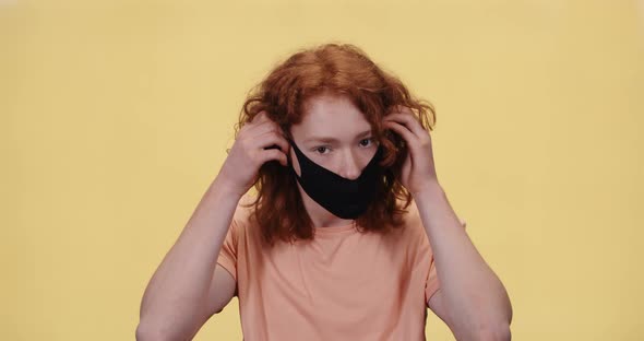 Young Boy Puts on a Protective Mask and Looks at the Camera, Portrait of a Red-haired Boy on a