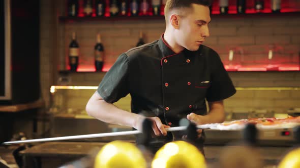 Pizzaiolo Putting Pizza in Stove at Restaurant