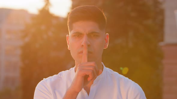 Young Man Eastern Businessman Hold Finger on Lips Look at Camera Makes Hush Gesture Sharing Hidden