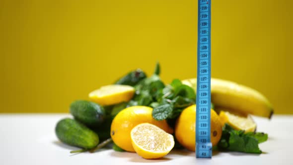 Closeup Measuring Tape Falling in Slow Motion on Table with Organic Fruits and Vegetables
