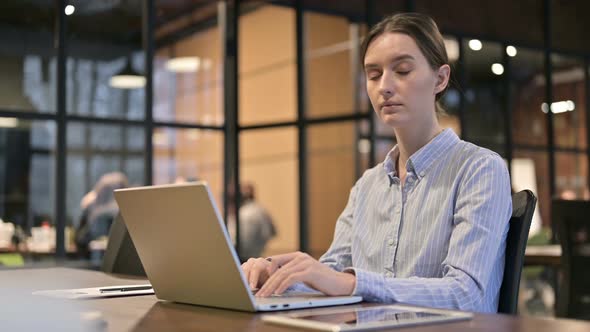 Woman Working on Laptop Looking Toward Camera