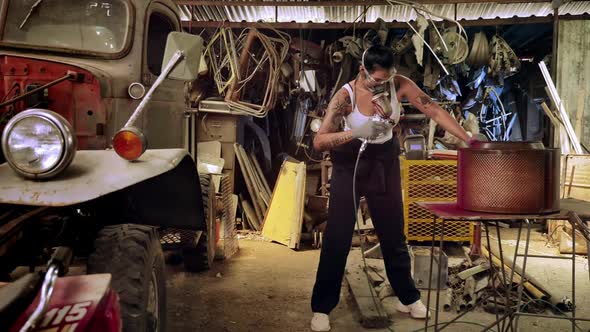 Attractive young woman mechanical worker repairing a vintage car in old garage.