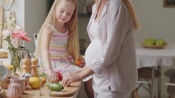 Happy Pregnant Woman Cooking with Little Daughter
