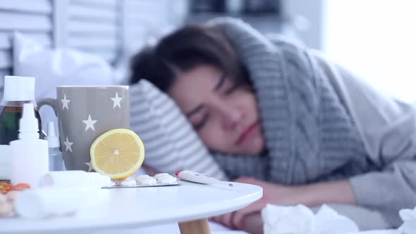 Sick Woman Lying On Bed With Flu At Grey Bedroom