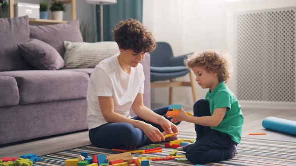 Happy Family Mom and Child Playing with Toys at Home Sitting on Floor Together