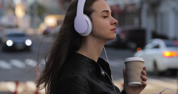 Modern Woman with Coffee Cup in City Listening To Music in Headphones, Lifestyle