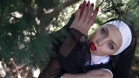 Sinful Woman is Dressed Like Catholic Nun Bright Makeup with Red Lips Posing at Nature Flirting with