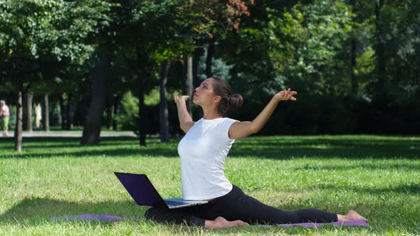 Girl Has a Yoga Practice in the Park with Laptop