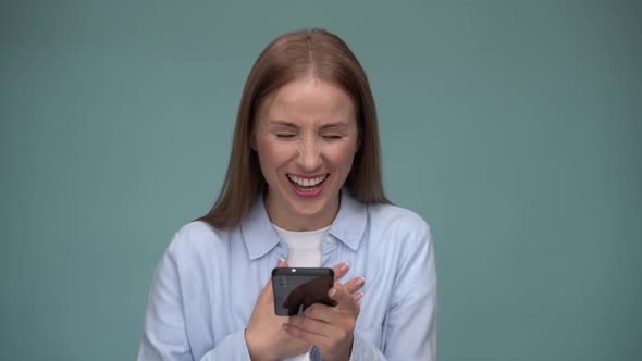 Happy woman scrolling her smartphone and laughing out loud while reading jokes.