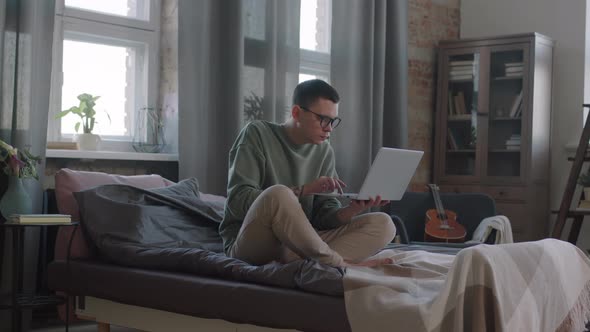 Man With Laptop Working In Bed