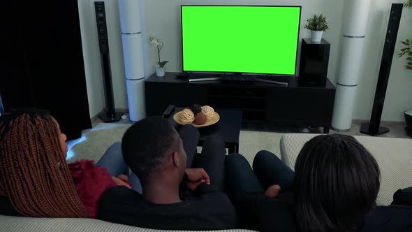 Three African Friends Watch Television in Living Room and Talk About Something - Green Screen