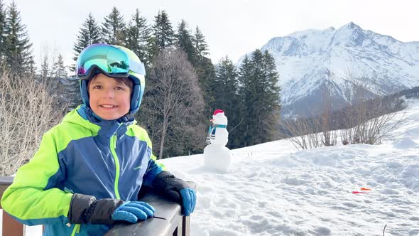 Little Boy with Ski Helmet and Mask on Balcony in Mountains