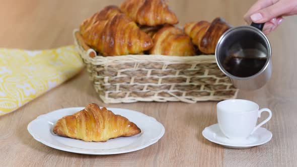 Cup of fresh coffee with croissants on wooden background, Pouring espresso into a cup