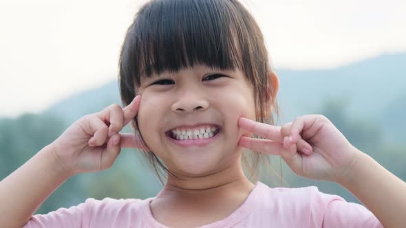 Portrait of a cute Asian preschooler smiling happily in the summer garden.
