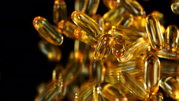 Super Slow Motion Shot of Falling Golden Capsules on Black Background at 1000Fps.