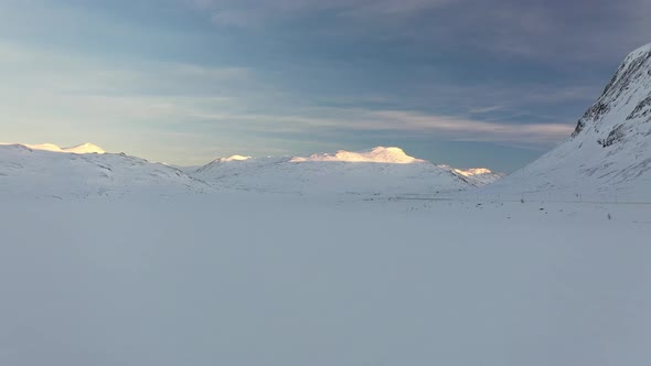 Forwarding winter aerial at Hemsedal mountain road crossing - Beautiful sunset and blue sky with car