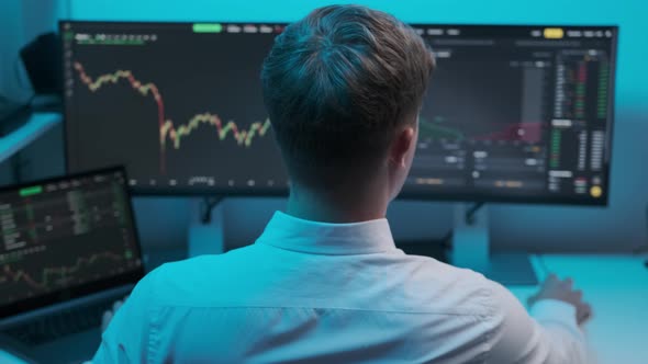 Close up of young Caucasian man trader working at monitor computer and browsing online in trading