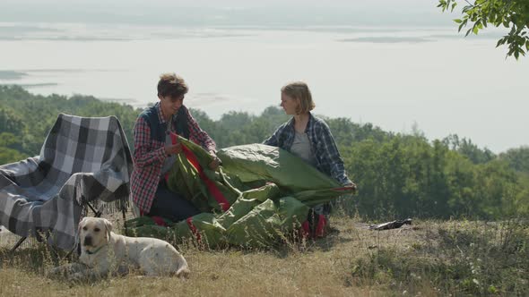 Young Adult Couple Puts Up Tent for Camping Outside