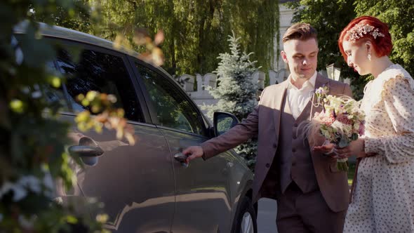 Young Groom Helps His Bride Get Into Gray Car