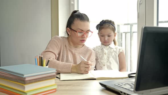 Mom Helps a Little Elementary School Student with Her Homework. The Child Is Happy. Back To School.