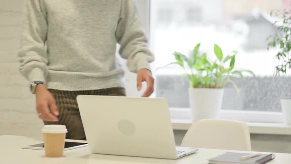 African Woman Coming Back Opening Laptop in Office