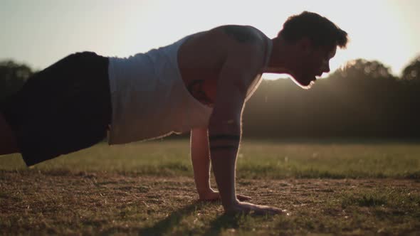 Man Doing Press Ups In The Park In The Evening Sun