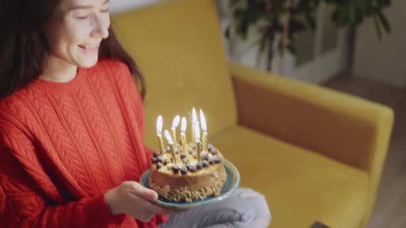 Happy Asian Multiracial Woman in Birthday Cap Celebrating Her Friend Blowing the Candles on Holiday