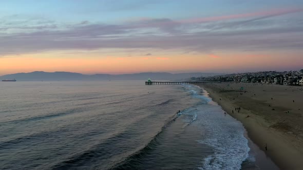 Serene Scenery At Manhattan Beach With Tourists On The Shore At Sunset - aerial drone shot