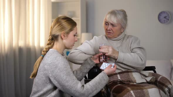 Young Woman Bringing Painkillers to Grandmother Feeling Headache, Family Care