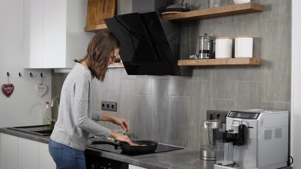 Beautiful Brunnete Girl Cooking Dinner in Home Kitchen, Frying on a Pan.