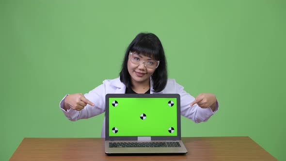 Beautiful Asian Woman Doctor Wearing Protective Glasses Showing Laptop and Giving Thumbs Up