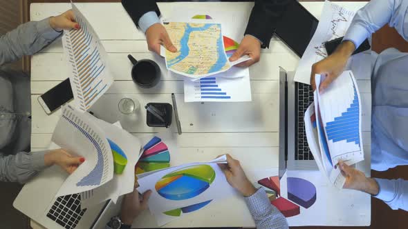 Top View to Hands of Business People Sitting at Table in Trendy Office and Examining Graphs