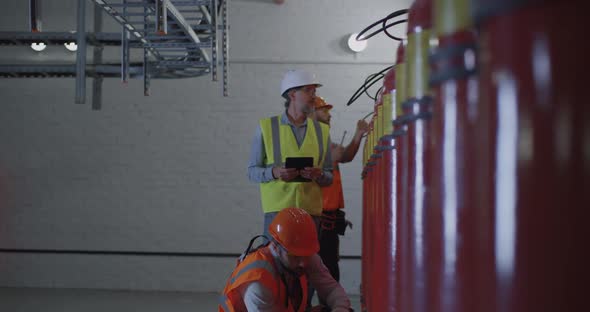 Mature Inspector Checking Workers Near Fire Extinguishers