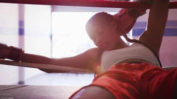 Mixed race woman resting in boxing gym