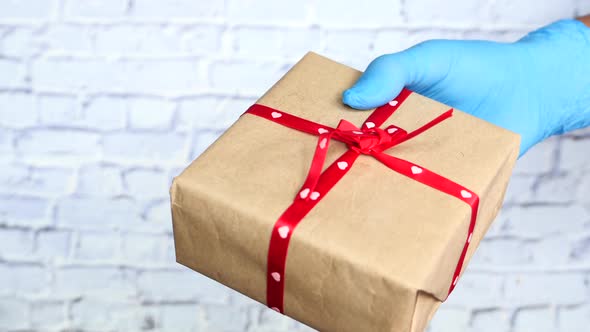 Male Hand in a Blue Medical Glove Gives a Gift