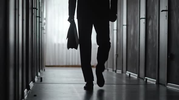 Silhouette of Confident Man Walking along Hallway