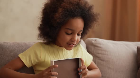 Portrait Little African American Girl Opens Gift Box and is Very Happy