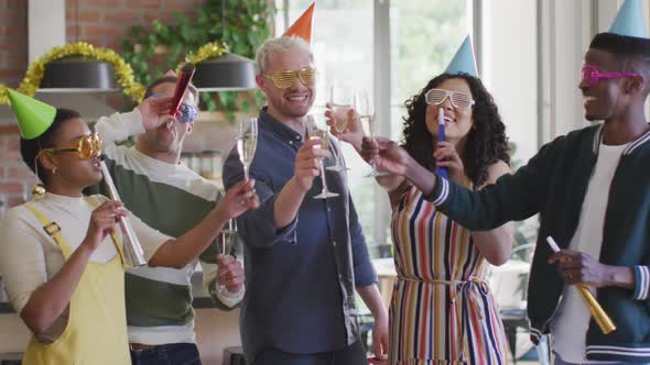 Happy group of diverse friends in party hats celebrating together, toasting with vine
