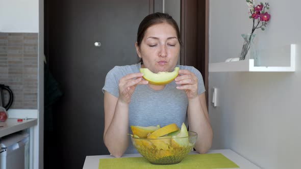 Woman Is Enjoying Eating Melon Sitting at Table on Small Kitchen