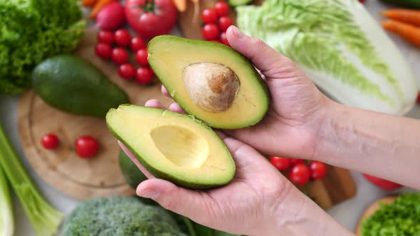 Healthy Vegan Food Concept. Hands Holding Fresh Green Avocado Cut In Half.