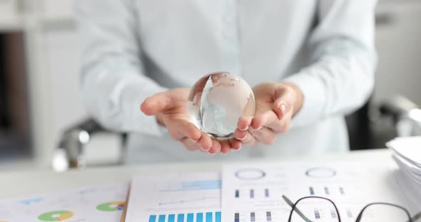 Woman Holding Glass Globe Over Documents with Graphs  Movie Slow Motion