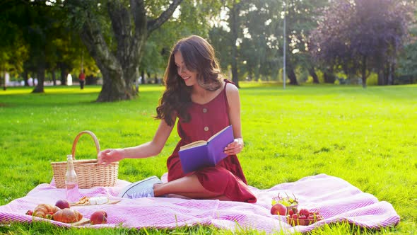 Happy Woman Reading Book at Picnic in Summer Park