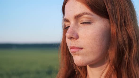 Beautiful Female Ginger Face with Freckles on Nature at Sunset