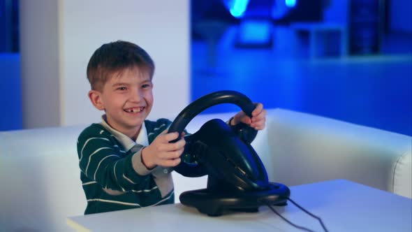 Happy Excited Little Boy Playing Videogame with Racing Wheel