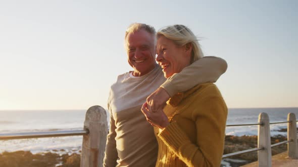 Senior couple embracing each other alongside beach