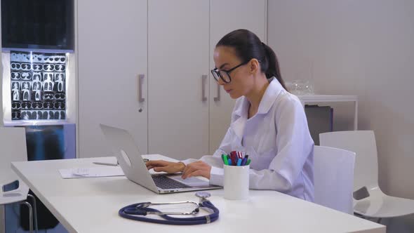 Female Physician Entering Data on Pc