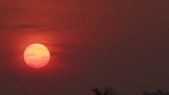 Large red sun slowly going under during sunset, close up