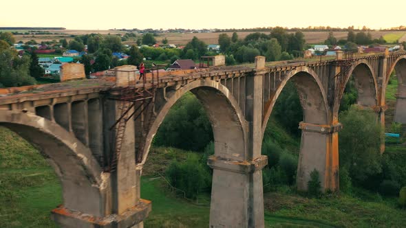 A Lady Is Jogging Along an Abandoned Bridge in the Distance