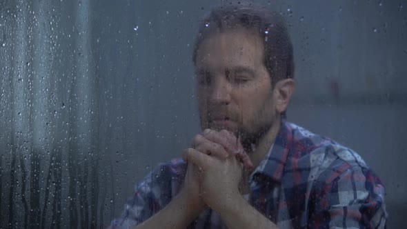 Hopeless Male Praying God Behind Rainy Window Asking for Help and Forgiveness